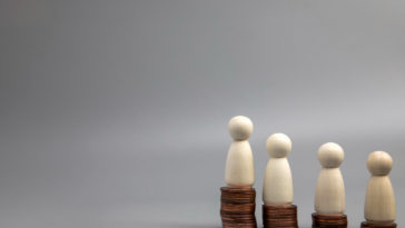 miniature people standing on coin stacks