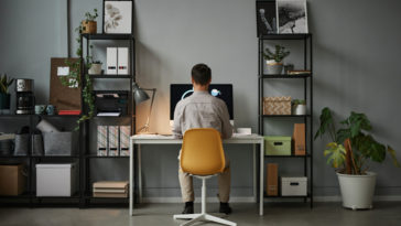 back view of a man using a computer in a home office