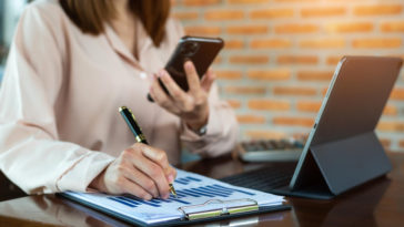 businesswoman with a phone and business report analyzing sales