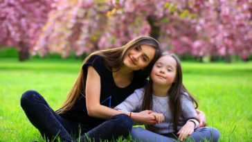 young woman and a little girl sitting on the grass in a park