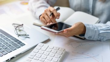 woman working at a desk with a phone, laptop and calculator