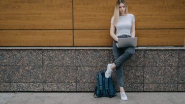 woman leaning on a wall with a laptop in her hands