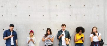 a group of young adults outdoors using smartphones