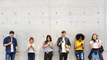 a group of young adults outdoors using smartphones