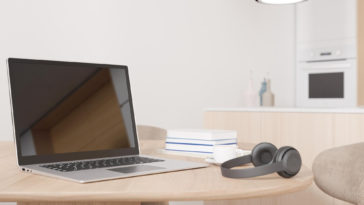 a laptop, headphones and books on a table in someone's home