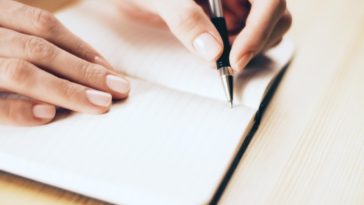 female hands writing with pen in a notebook