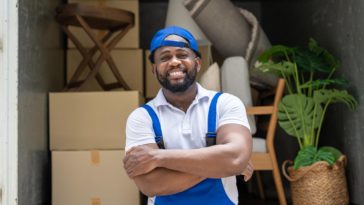 mover standing at the back of a truck with moving boxes and furniture in it