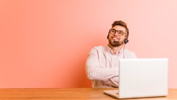 man with headset working on a laptop from home