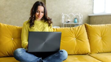 girl working from home on a couch with a laptop in her lap