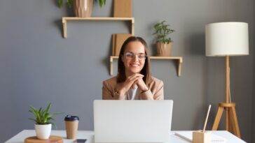 smiling woman working on a laptop from a home office