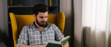 man sitting in a yellow chair reading a book